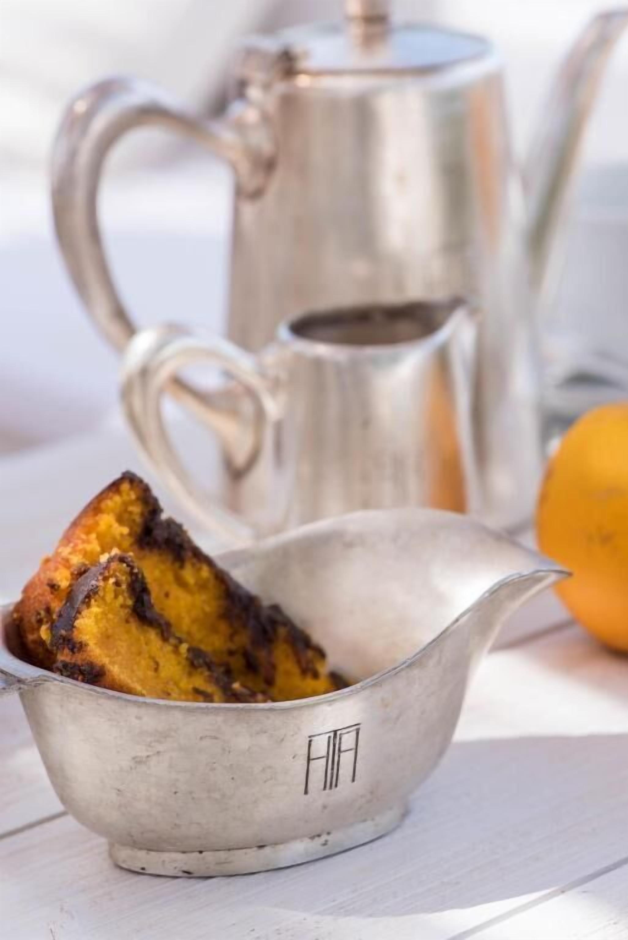 A metal teapot and a metal cup with a piece of food inside.