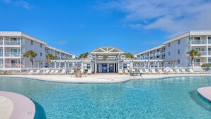 Ein Hotel mit zentralem Pool, mehreren Balkonen und blauem Himmel.