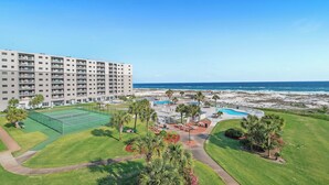 Ein Hotel mit Tennisplatz, Pool und Blick auf den Strand.