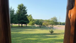 A wooden deck with a view of a grassy field and trees.