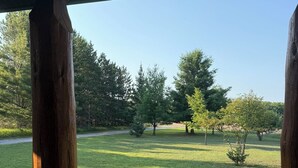 A wooden deck with a view of a grassy lawn and trees.
