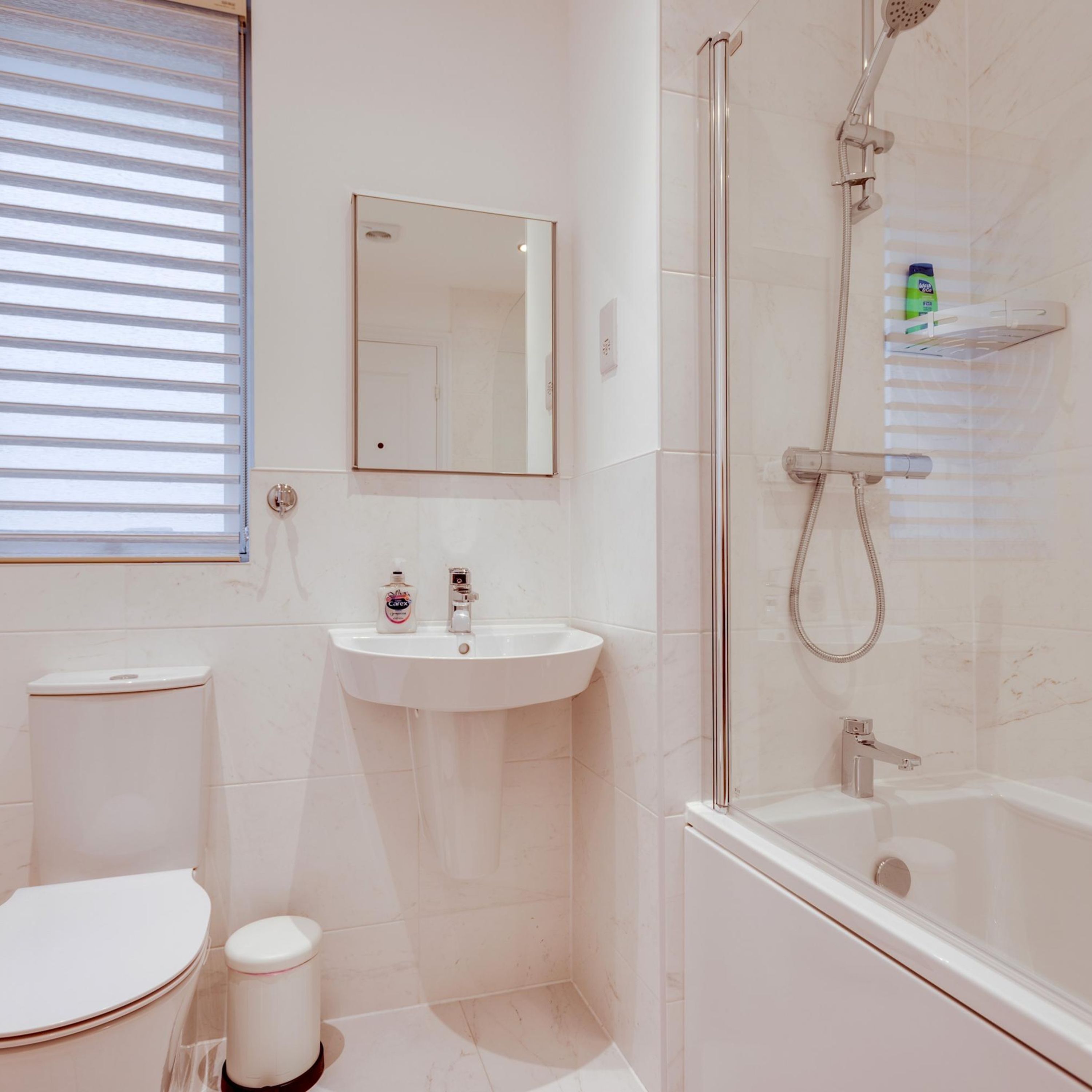 A bathroom with a toilet, sink, mirror, shower, and bathtub.