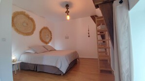 Un dormitorio con una cama, una escalera de madera y un accesorio de luz en el techo.