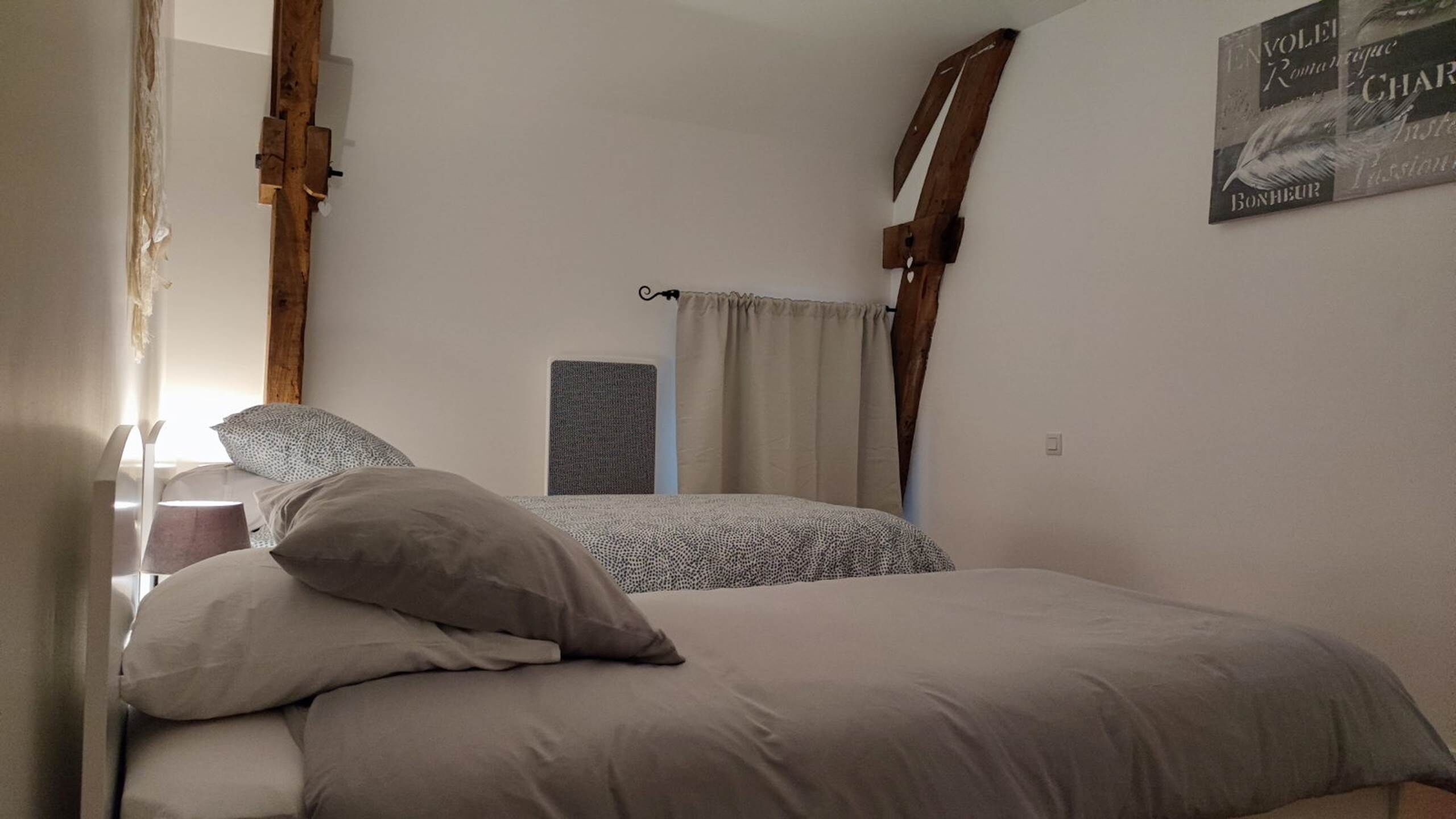 Une chambre à coucher avec un lit, des oreillers, une table de chevet, une lampe et une étagère fixée au mur.