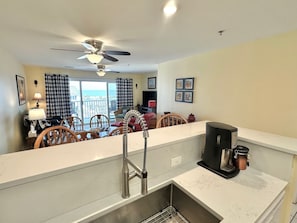 A modern kitchen with a built-in dishwasher, a coffee maker, and a dining area with a table and chairs.
