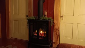 Puuta polttava kamiina, jossa on koristeellinen yläosa, on sijoitettu puisen oven eteen. Ovessa on punainen paneeli.