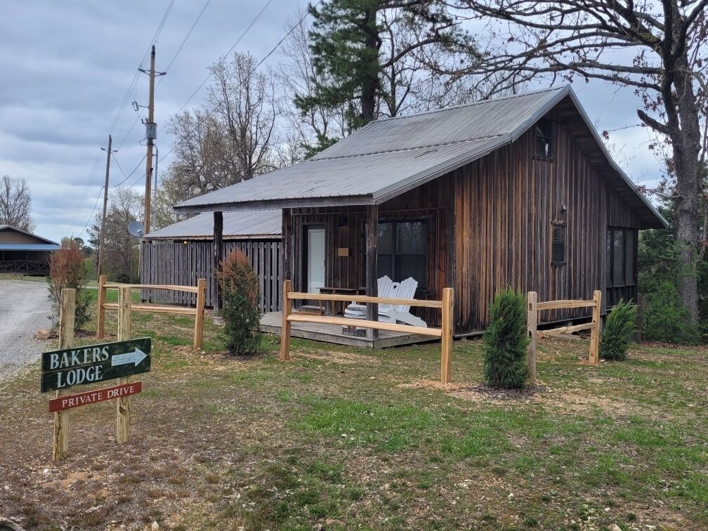 Un rustico lodge in legno con tetto spiovente, un portico con ringhiere in legno e un segnale che indica un accesso privato.
