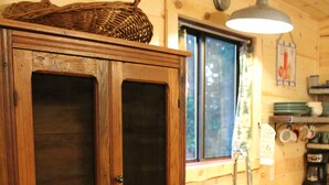 Een houten kast met glazen deuren, een houten aanrecht met een wastafel en een hangende lamp.
