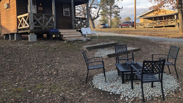 A rustic cabin with a porch, a fire pit, and outdoor seating.