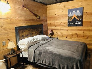 Een houten kamer in chaletstijl met een bed, een lamp en een poster aan de wand.