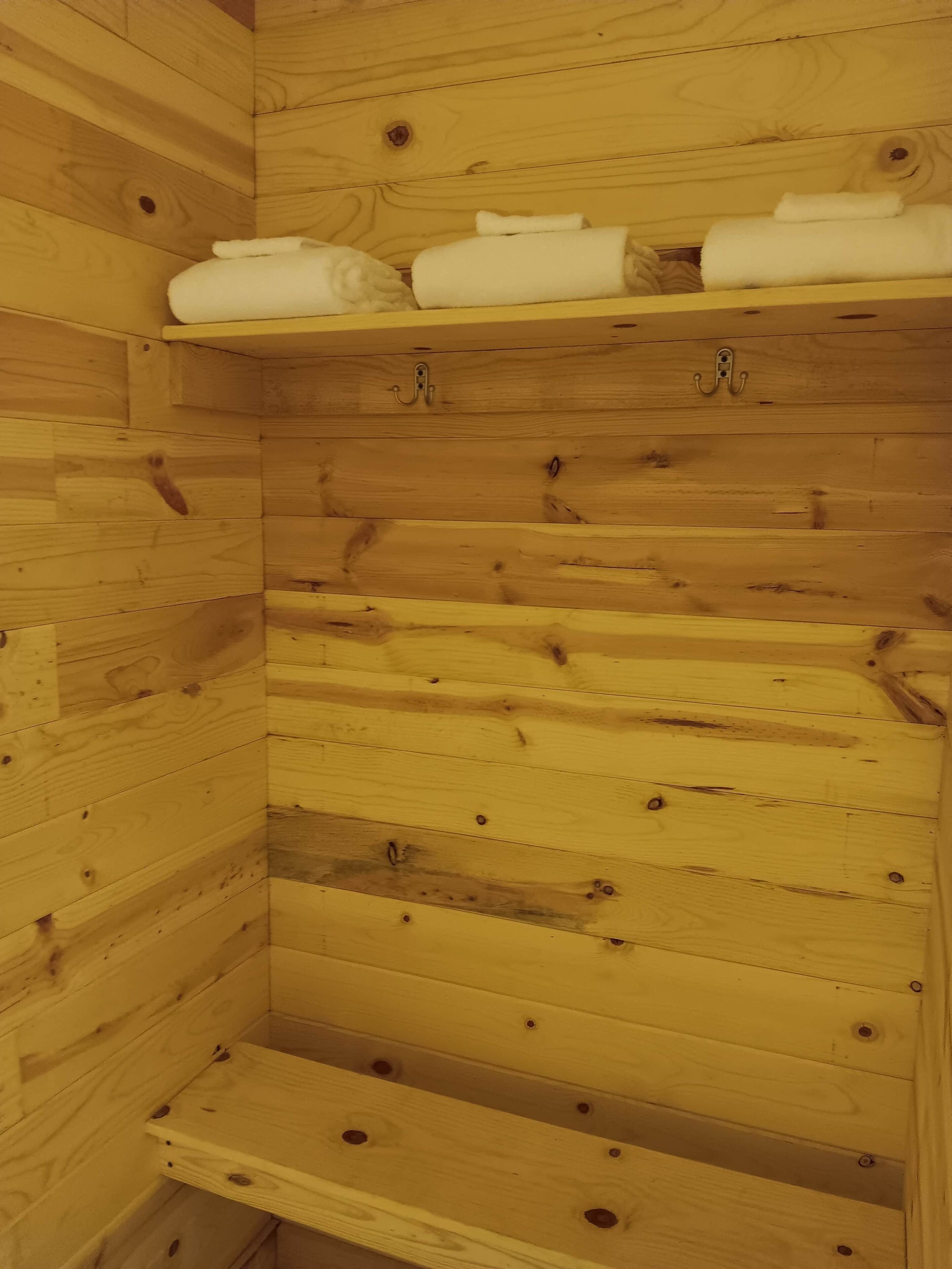 A wooden cabin interior with a shelf holding folded towels.