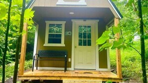 A small wooden cabin with a porch, two windows, and a door.