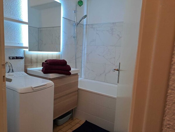 A bathroom with a white sink, a mirror, a shower, and a towel rack. - Small nest overlooking the ponds (Palavas-les-Flots)
