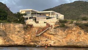 A modern coastal house with a stone staircase leading to a balcony overlooking the sea. - Luxurious 6-Bedroom Villa with Private Pier & Panoramic Ocean View (Jeremi)