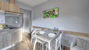 Una cocina moderna con un armario de madera, una campana extractora de acero inoxidable y un comedor con una mesa dispuesta para cuatro personas.