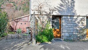 Un edificio con fachada de piedra, una puerta y un pequeño jardín con una mesa y sillas.