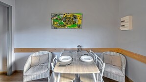 Un comedor con una mesa de madera, sillas blancas y un cuadro en la pared.