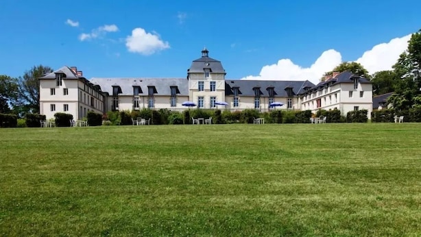 A large, historic building with a symmetrical facade, multiple windows, and a central tower. - Kergonano - Parking privé et piscine (Baden)