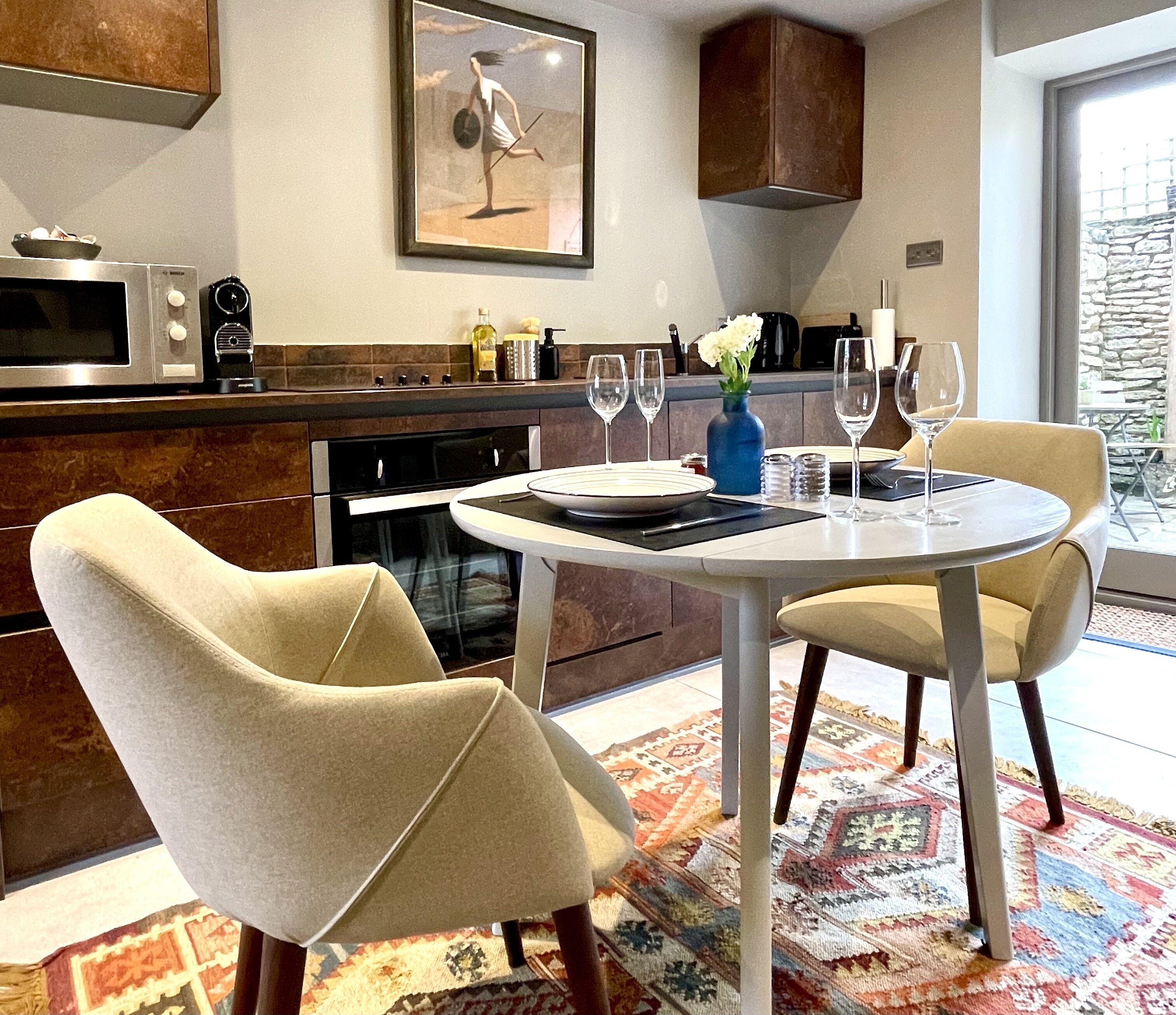 Une cuisine moderne avec un coin repas, comprenant une table ronde, des chaises et une vue sur l’extérieur.