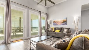 A spacious living room with a gray sofa, a coffee table, and a painting on the wall.