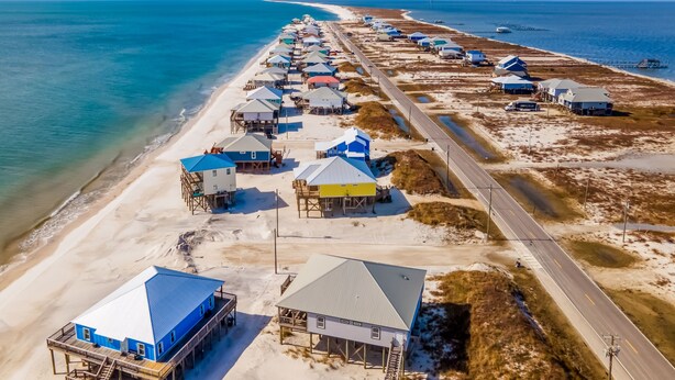 An aerial view of a coastal area with multiple beach houses and a road.