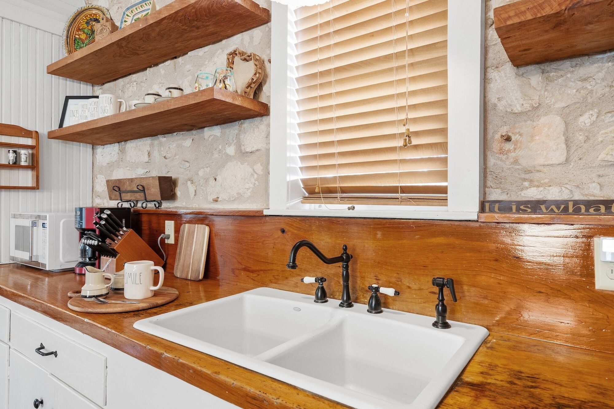 Una cocina con un lavamanos doble, encimeras de madera y un salpicadero de piedra.