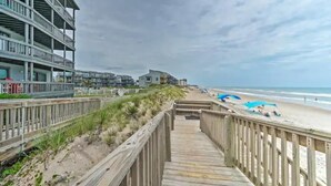 A wooden boardwalk leading to a beach with a building on the left and a clear sky above. - Oceanfront North Topsail Beach Condo w/Pool! Linens and towels provided (North Topsail Beach)