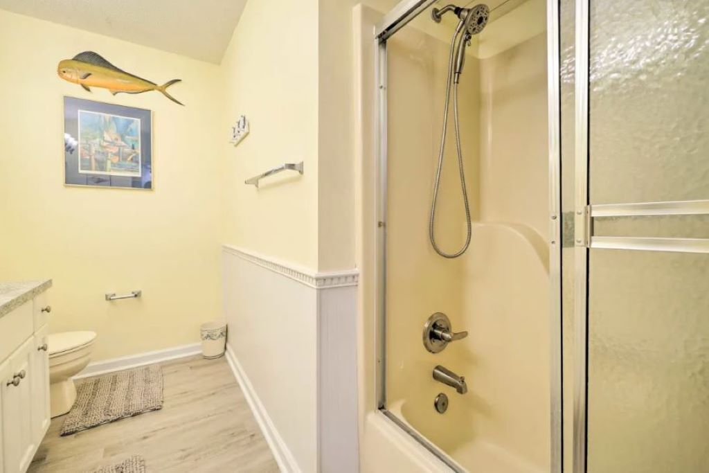 Une salle de bain avec une douche à parois de verre, des toilettes, un lavabo et un tableau encadré au mur.