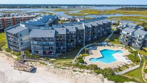 A modern apartment complex with multiple buildings, a central swimming pool, and a beach area. - Oceanfront North Topsail Beach Condo w/Pool! Linens and towels provided (North Topsail Beach)