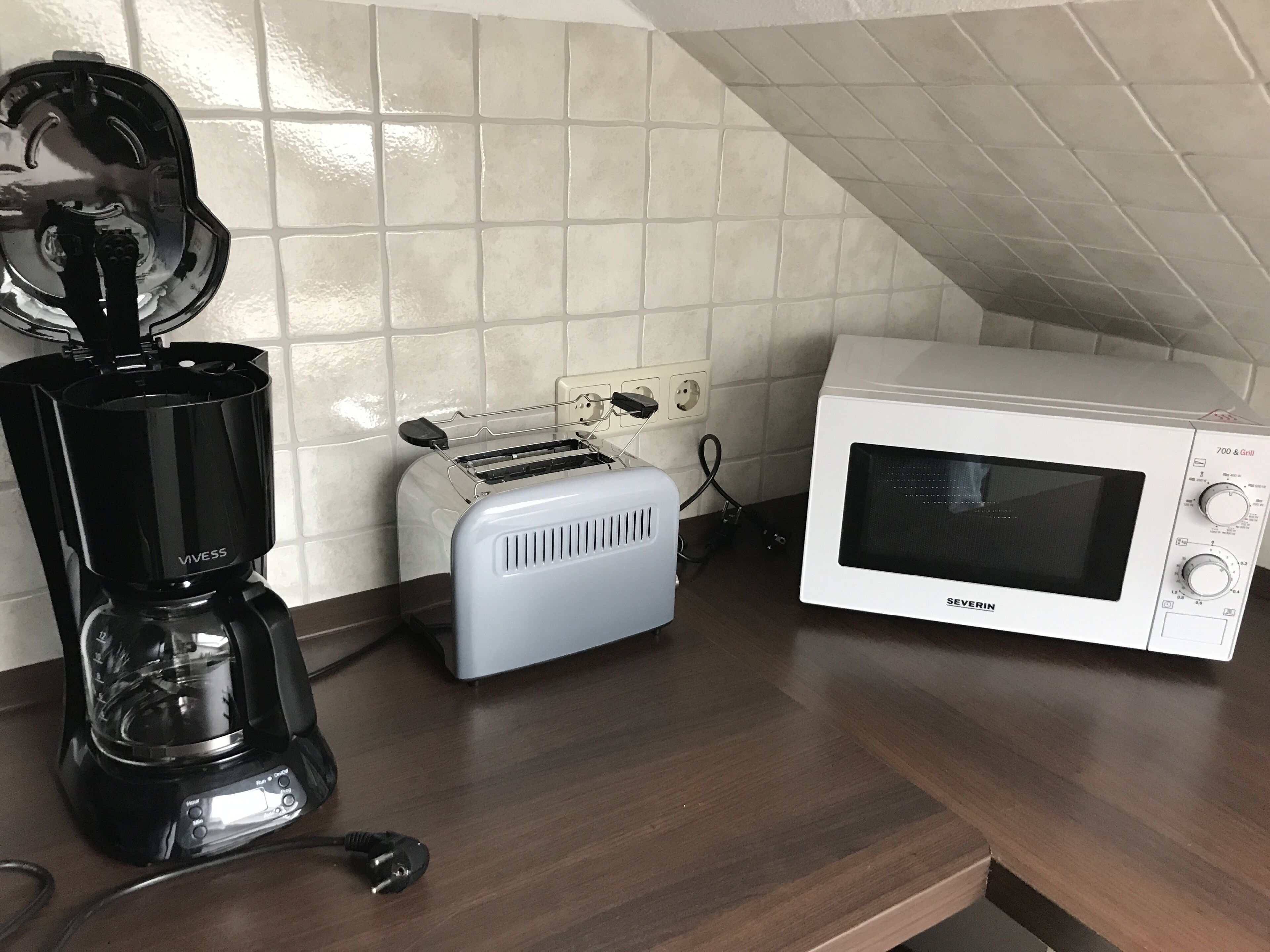 Eine Küche mit einem Toaster, einer Kaffeemaschine und einer Mikrowelle auf einer Holzausziehtischplatte.