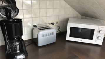 Eine Küche mit einem Toaster, einer Kaffeemaschine und einer Mikrowelle auf einer Holzausziehtischplatte.