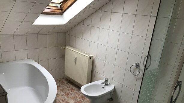 A bathroom with a bathtub, a sink, a shower, and a radiator. - Wooden Roof, 95 qm, 5 Pers (Attendorn)