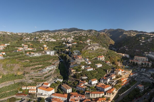 Une ville située sur une colline, avec des vignobles en terrasses, des bâtiments aux toits de tuiles rouges et une route sinueuse.