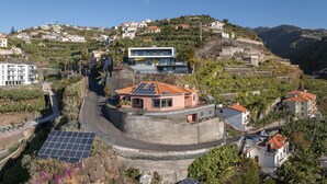 Una zona residencial en una ladera con casas, un edificio moderno con techo rojo y paneles solares.