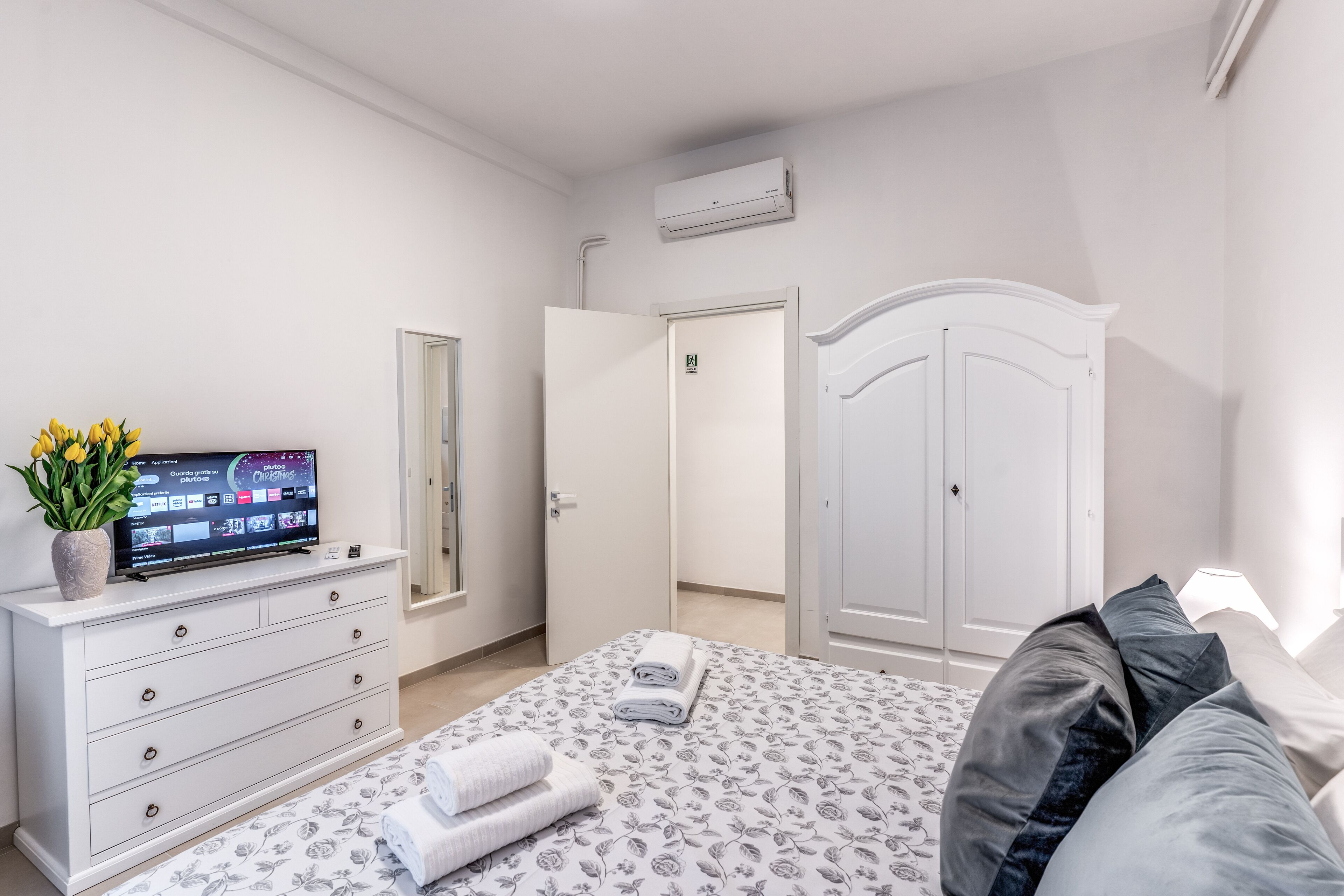 Un dormitorio con cama, cómoda, televisor y armario.