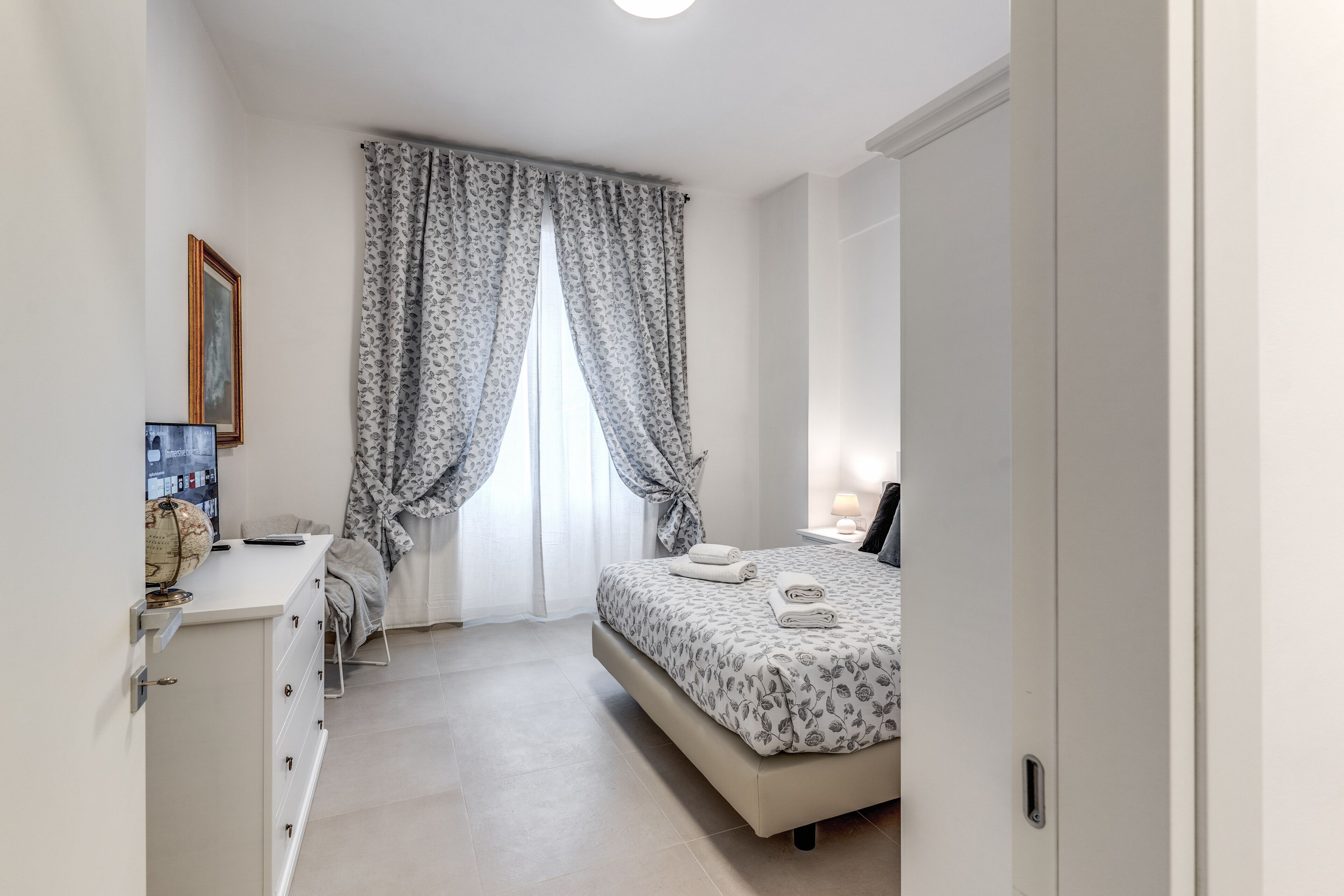 A bedroom with a bed, a desk, a globe, and a framed picture on the wall.