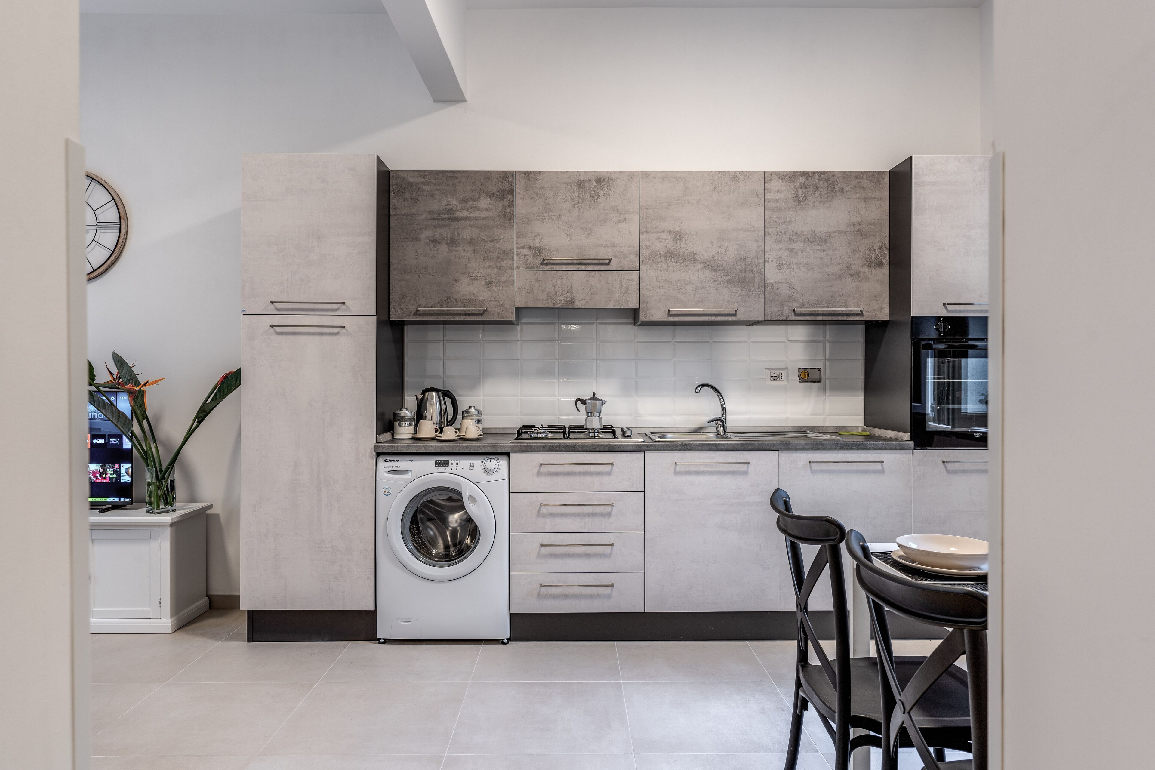 Une cuisine moderne équipée d’un lave-linge intégré, d’un évier et d’une cuisinière.