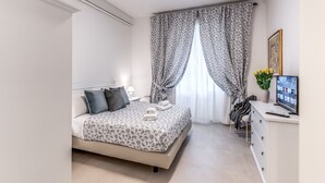 A neatly arranged bedroom with a bed, bedside table, and a desk with a computer. - PMT APT (Rome)