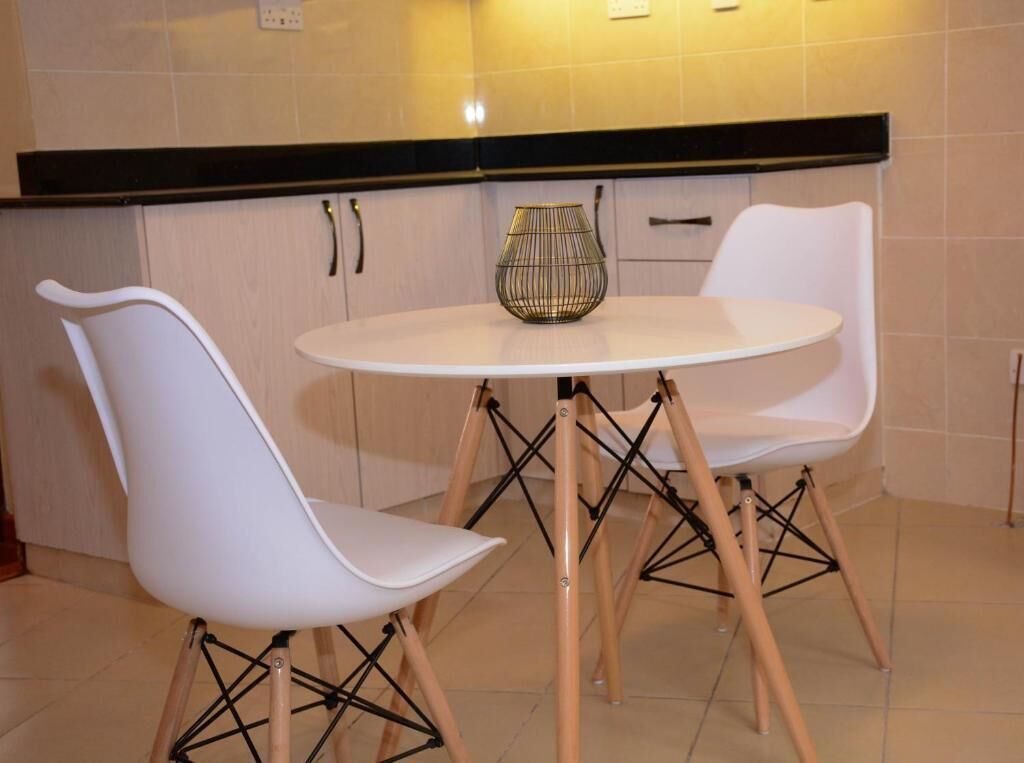 Una cocina moderna con sillas blancas, una mesa redonda y un jarrón decorativo.