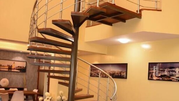 A spacious living area with a spiral staircase, a dining table, and comfortable seating.