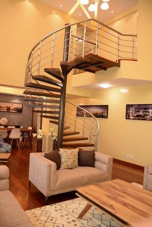 A spacious living area with a spiral staircase, a dining table, and comfortable seating. - Lux Suites Westlands Penthouse (Nairobi)
