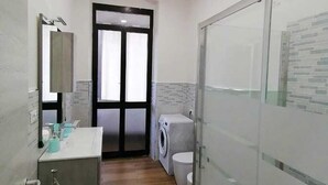 A compact bathroom with a sink, mirror, and a glass shower enclosure. - Calypso Holiday Home, cozy apartment in Station area for 5 Terre (La Spezia)