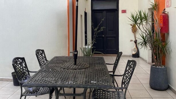 Un patio con mesa y sillas, una sombrilla y plantas en macetas.