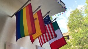 Una fila de banderas en una pared, incluyendo la bandera estadounidense, la bandera mexicana y la bandera de El Salvador.