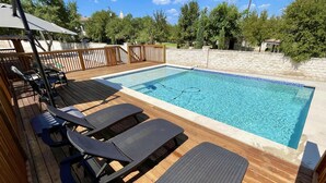 En swimmingpool med liggestole og en træterrasse.