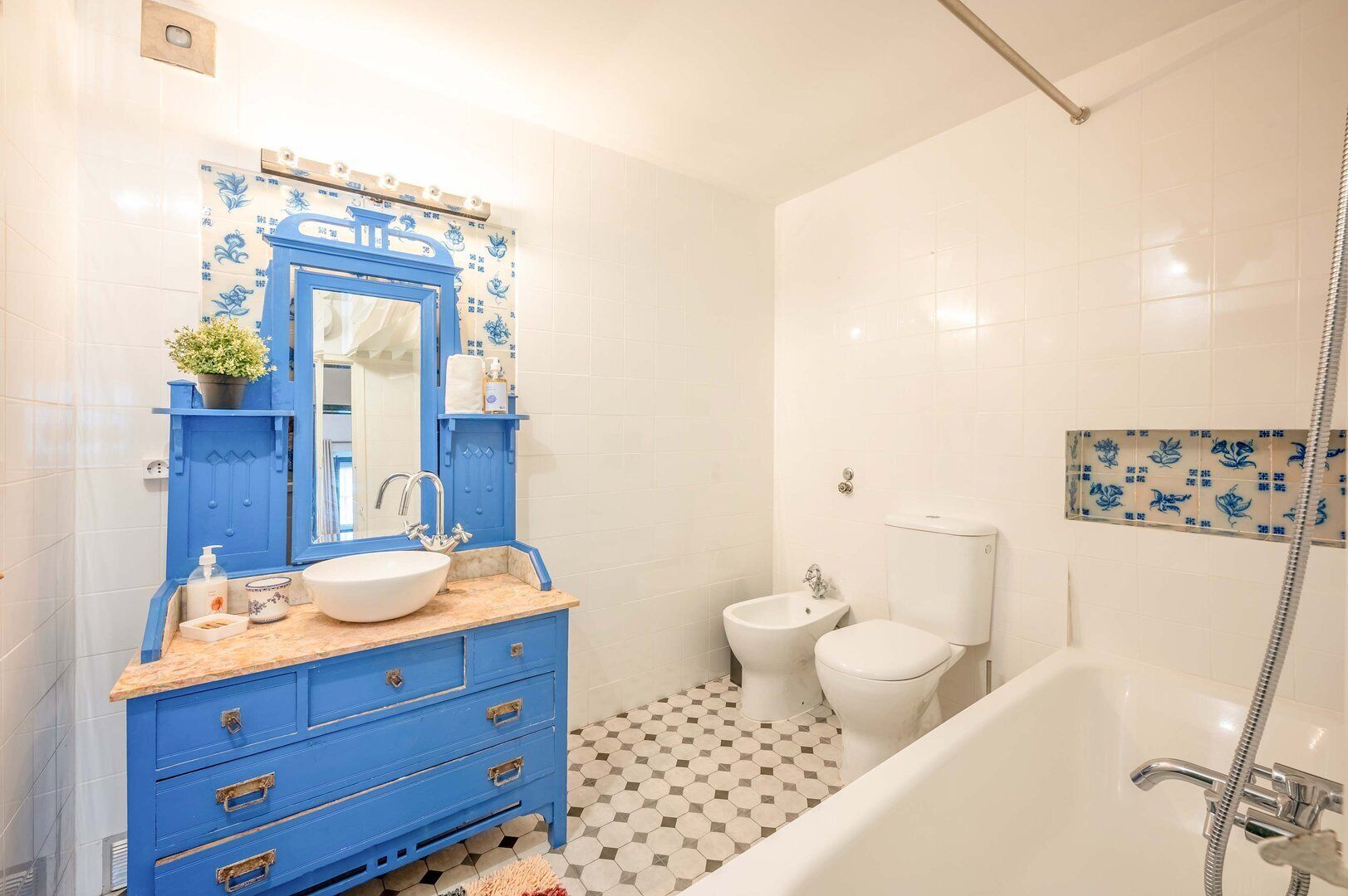 Un baño con un tocador azul, un lavabo blanco, un espejo, un bidé, un inodoro y una zona de ducha.