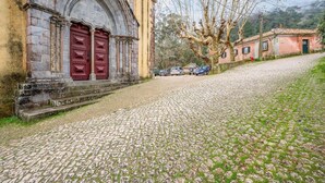 Een geplaveid straatje dat leidt naar een historisch gebouw met een rode deur en een stenen boog.