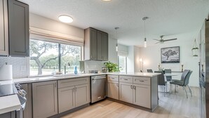 Una cocina moderna con electrodomésticos integrados, un comedor con mesa y sillas, y un ventilador de techo.
