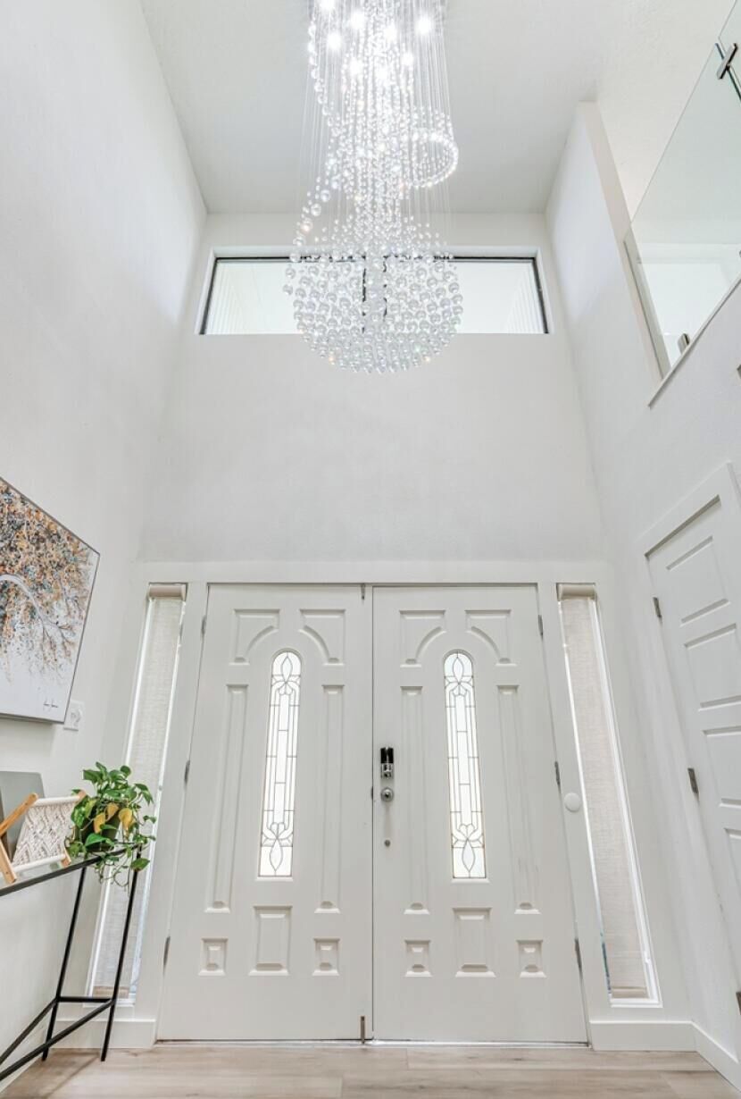 A white door with a glass panel and a chandelier above.