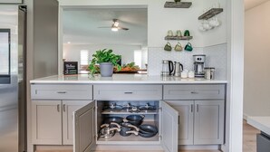 Una cocina con estufa integrada, ventilador de techo y encimera con diversos utensilios de cocina.